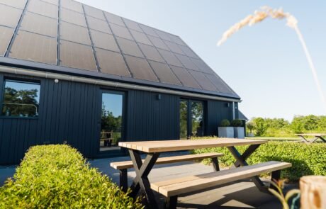 Houten picknicktafel op het terras langs de zwarte schuurwoning