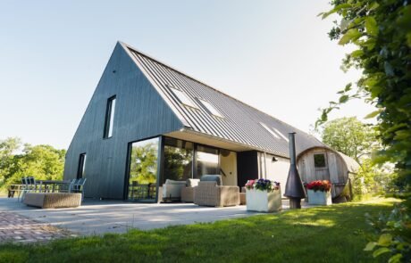 De zwarte schuurwoning met barrelsauna in het gouden avondlicht