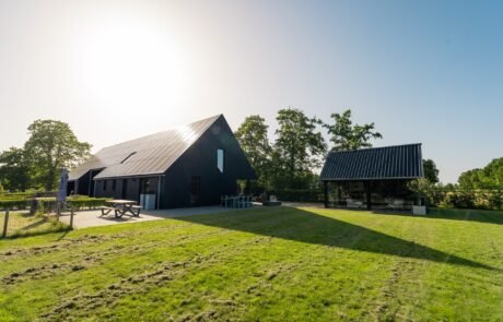 Zicht op de schuurwoning en tuinkamer vanaf het omliggende weiland