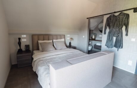 Slaapkamer met tweepersoonsbed en de eigen badkamer achter de kamerwand