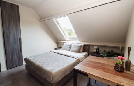 Slaapkamer met dakraam, houten tafel en tweepersoonsbed