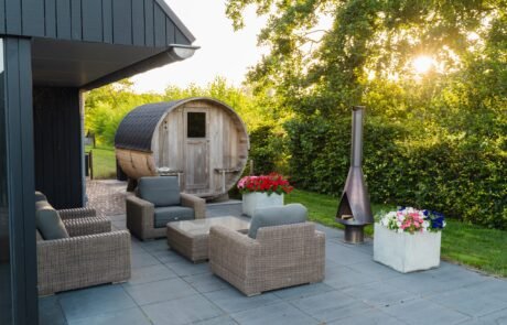 Terras met loungeset, vuurkorf en barrelsauna in de avondzon