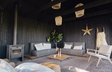 Tuinkamer met loungebanken en houtkachel, gebouwd met balken van de oude boerderij